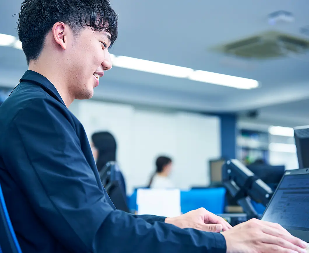 写真：社内の席でノートパソコンを操作している